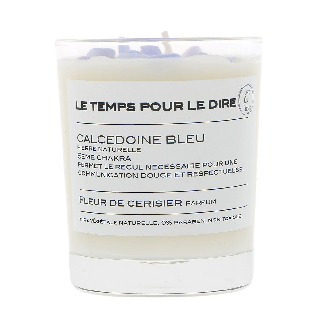 Bougie parfumée LE TEMPS POUR LE DIRE avec pierres de calcédoine bleue, indiquée pour le 5ème chakra, parfumée à la fleur de cerisier, présentée dans un pot en verre. La bougie est fabriquée à partir de cire végétale naturelle, sans parabène, et non toxique.