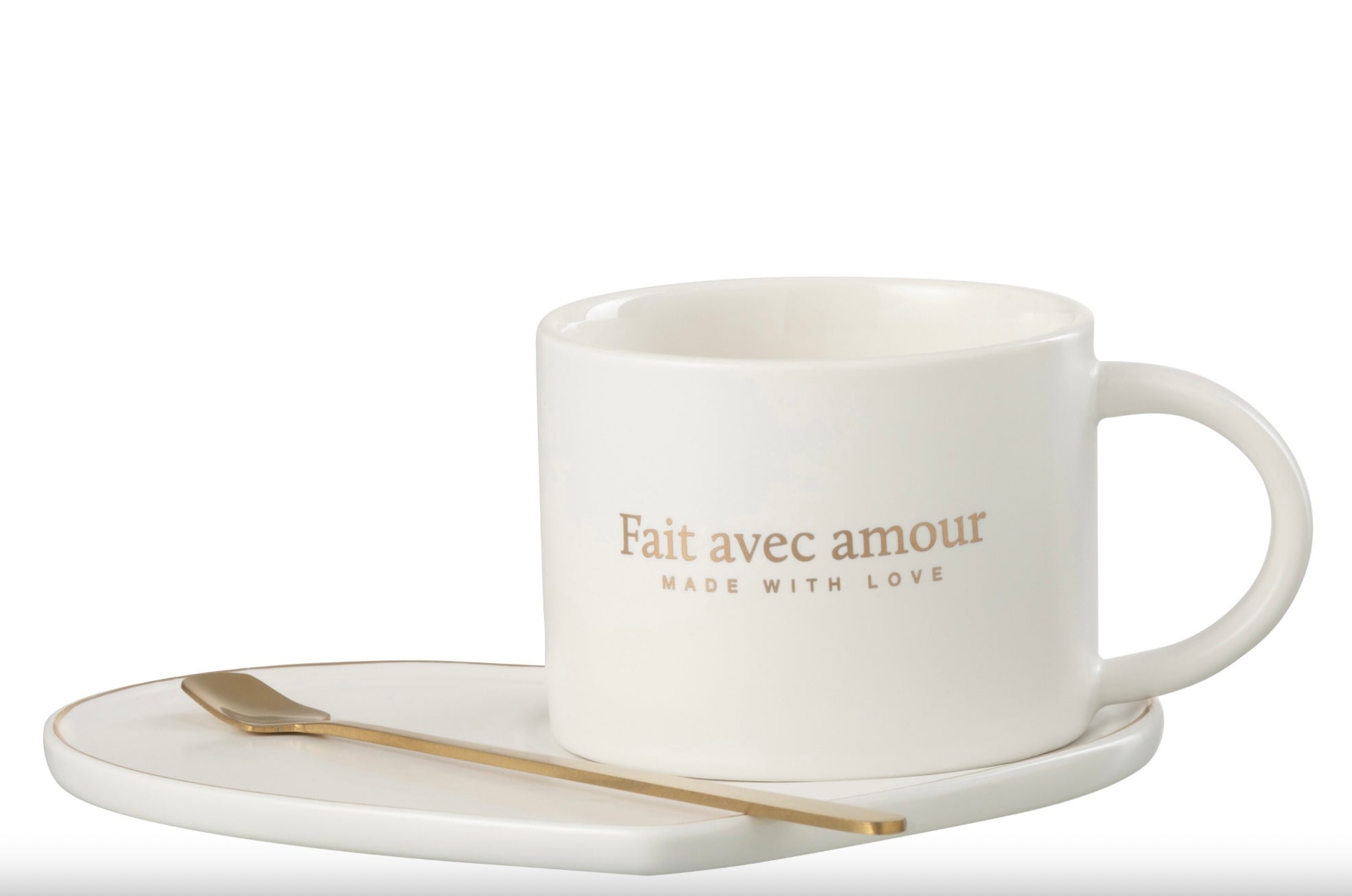 Tasse en porcelaine blanche avec l’inscription ‘Fait avec amour’ en doré, accompagnée d’une soucoupe en forme de cœur et d’une cuillère dorée, disposées côte à côte.