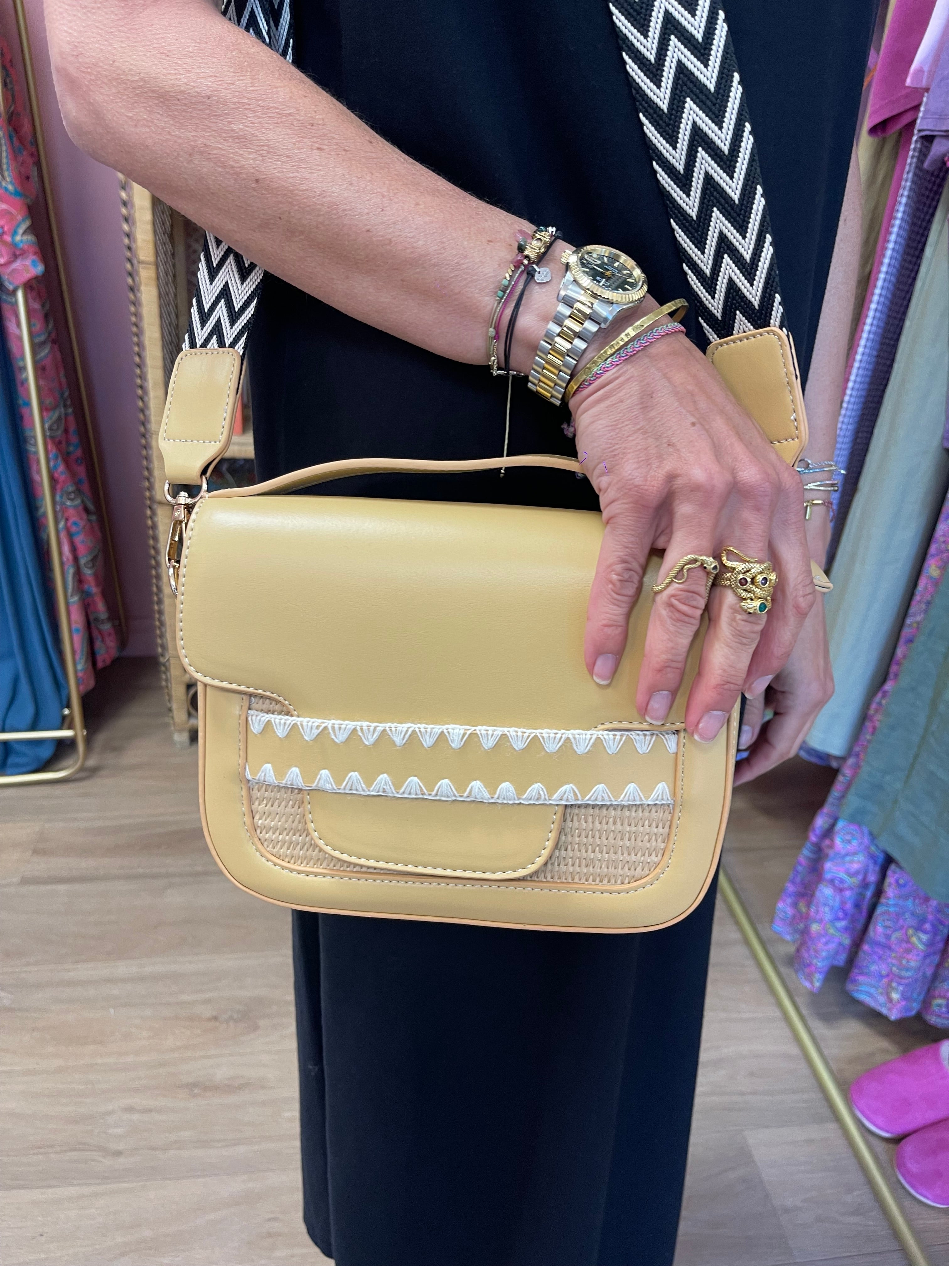 Sac à bandoulière jaune ROME avec des détails en paille tressée et une sangle à motifs en zigzag noir et blanc.